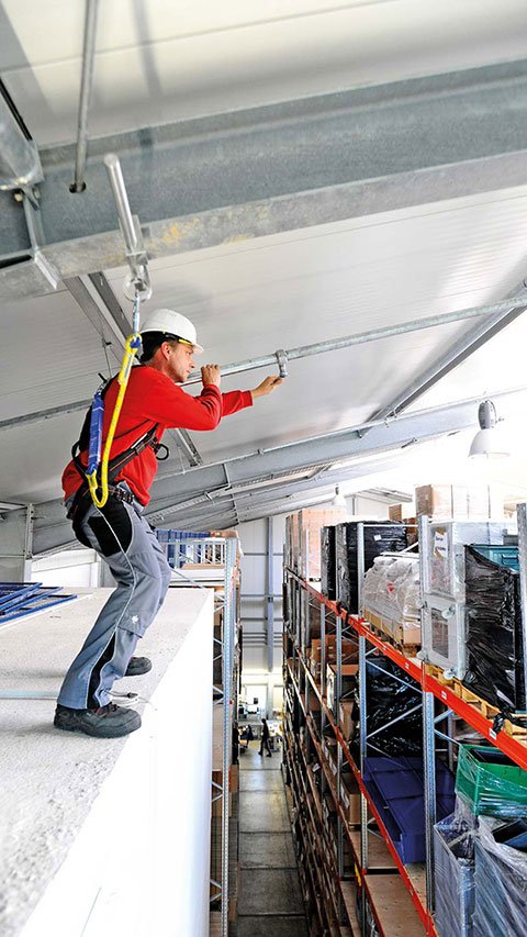 Foto eines Industriearbeiters, der mit mobilem Sekuranten am Stahlträger gegen Absturz angeleint ist.