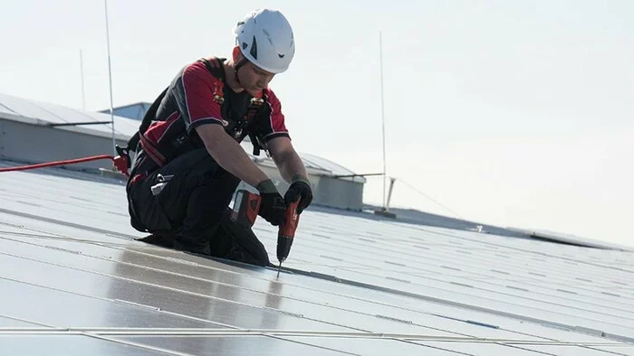 Das Bild zeigt einen Arbeiter an einer Photovoltaikanlage, der sich zur Absturzsicherung an einem Sekuranten angeleint hat.